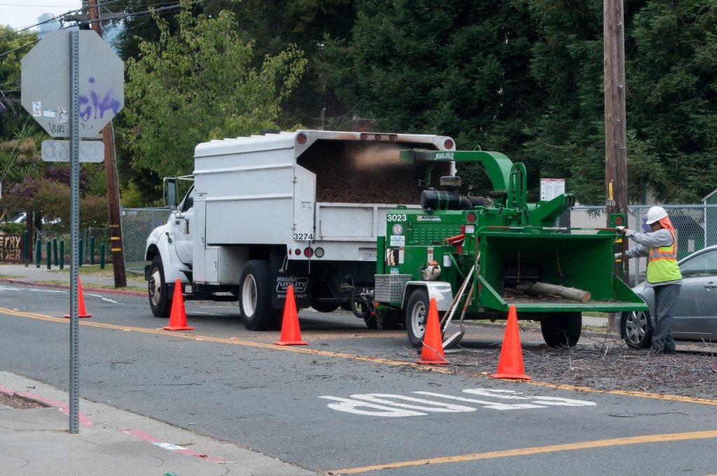 Crew feeding branches into a wood chipper on a residential street